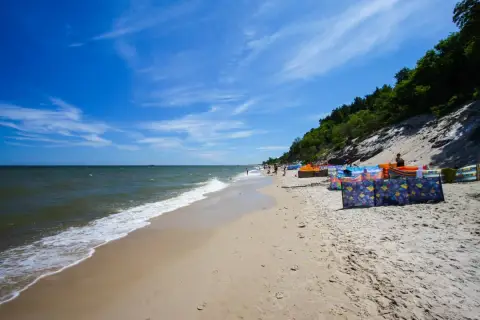 Słoneczna plaża w Chłapowie z kolorowymi parawanami, idealne miejsce na rodzinne wakacje i atrakcje dla dzieci.